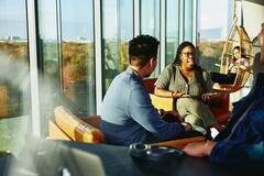 Two people having a conversation while sitting down in a lounge environment.