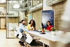 Three colleagues having a meeting in a meeting room, while one colleague is making a call outside the room.