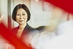 Woman in suit smiling. Japan. Primary color: red.