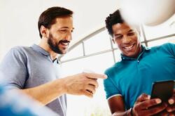 Two smiling colleagues (men) looking at a phone.