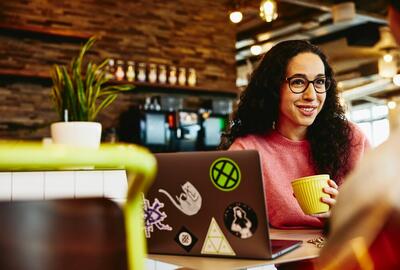 Close up - Smiling woman holding a mug while talking to someone.