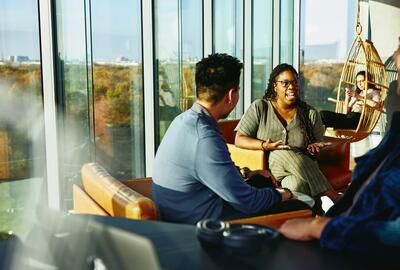 Two people having a conversation while sitting down in a lounge environment.