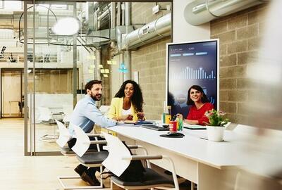 Three colleagues having a meeting in a meeting room, while one colleague is making a call outside the room.