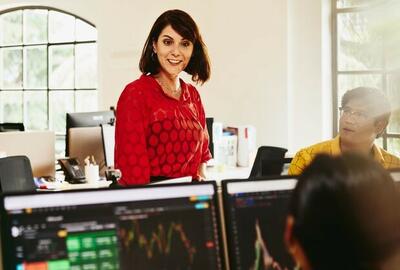 Smiling woman talking to colleagues, standing between desks.