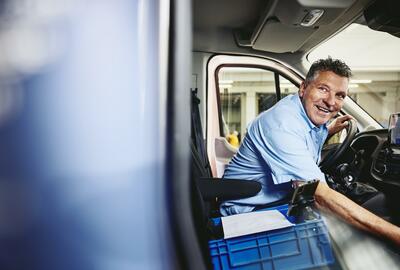 Smiling man sitting in driver's seat of a logistics truck