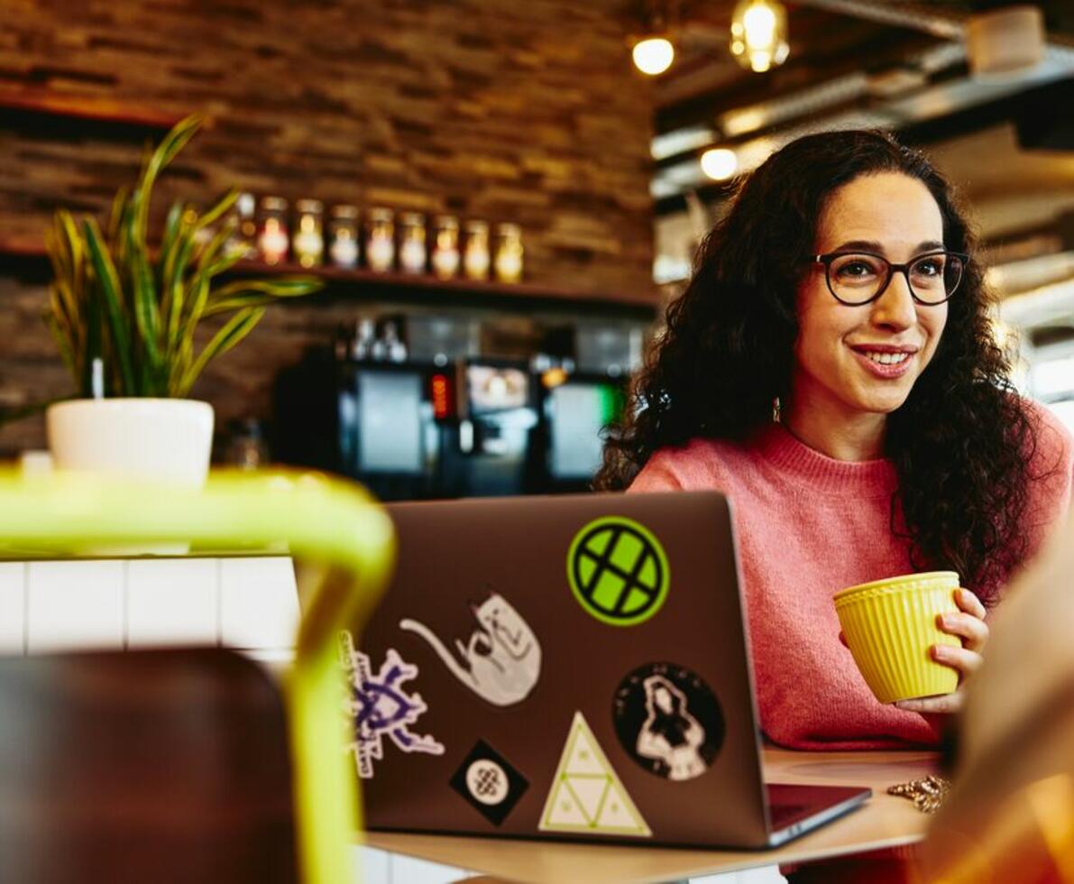 Close up - Smiling woman holding a mug while talking to someone.