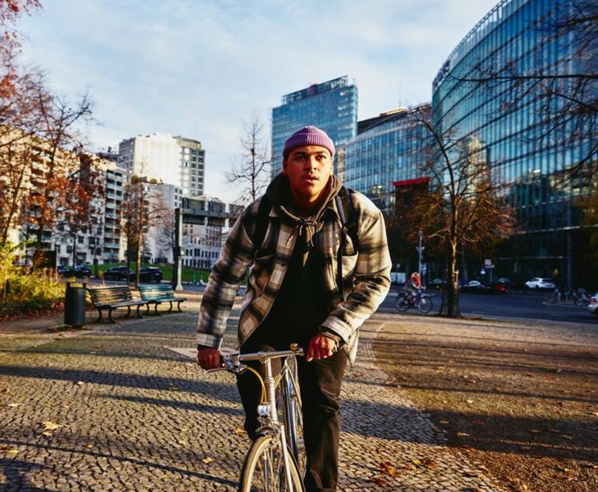 Cycling man, autumn trees and office buildings on the background.