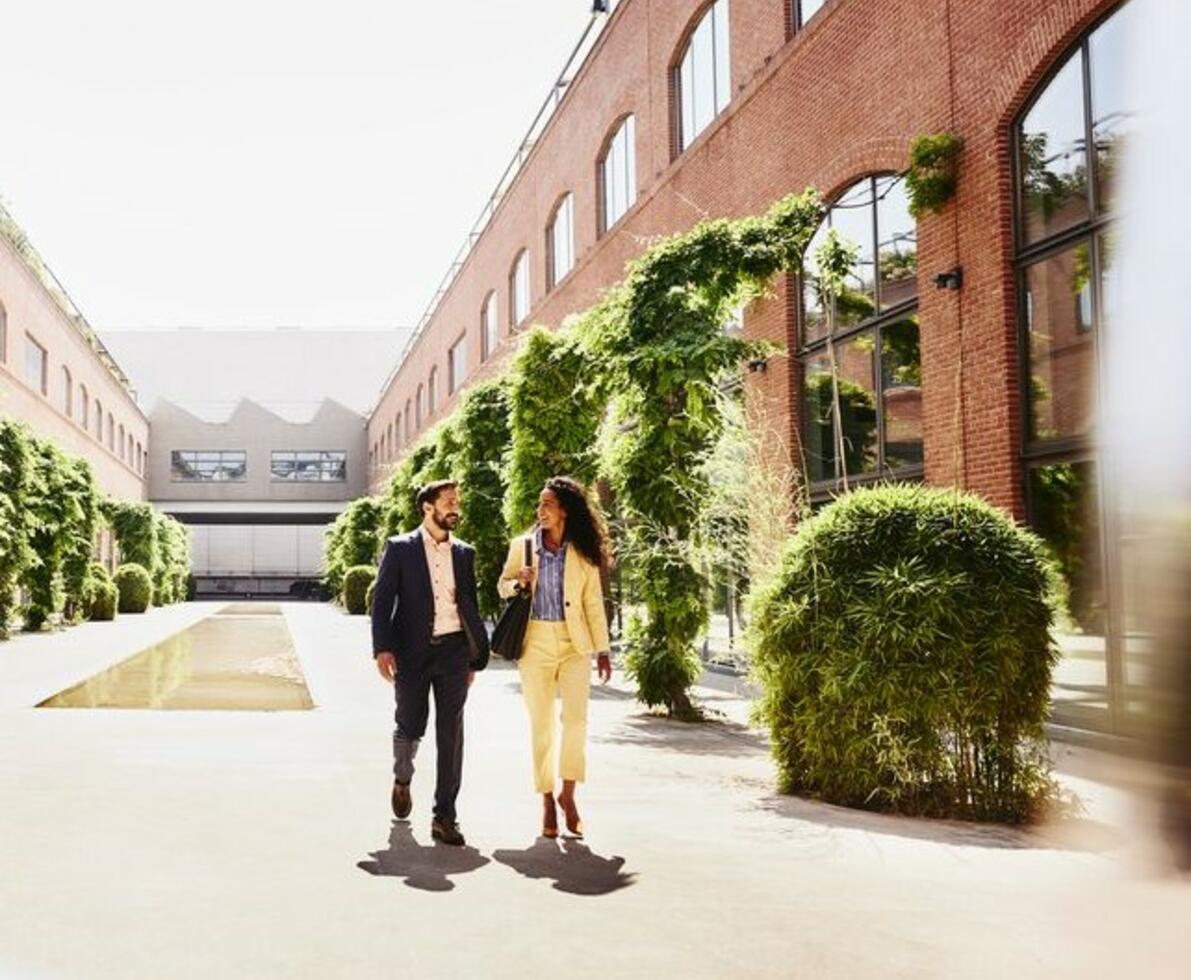 Man and woman walking outside between office buildings.