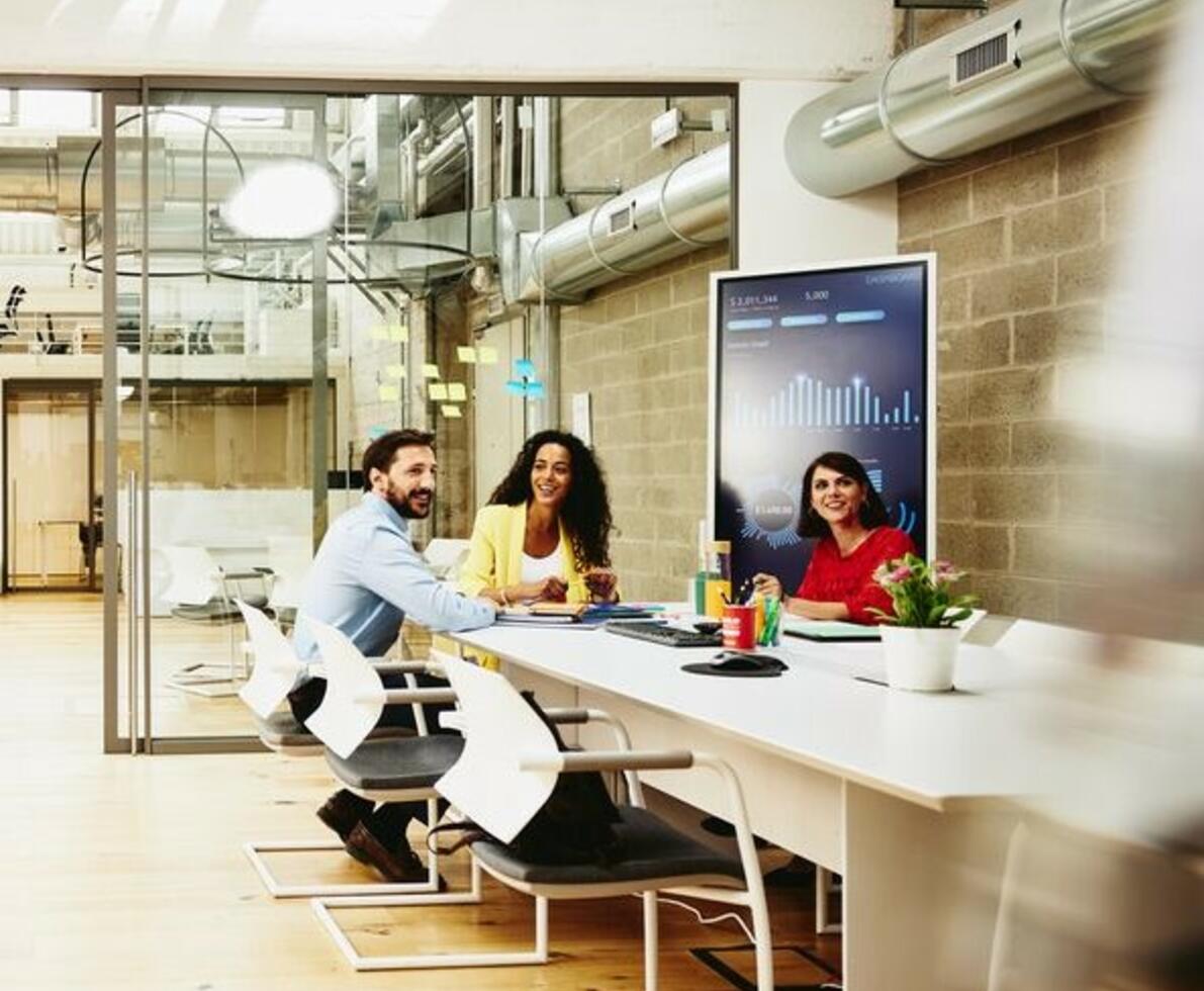 Three colleagues having a meeting in a meeting room, while one colleague is making a call outside the room.