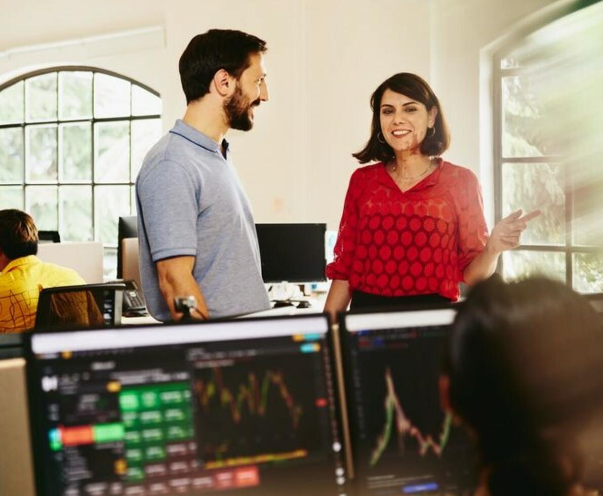 Two colleagues man and woman having a chat standing between desks.