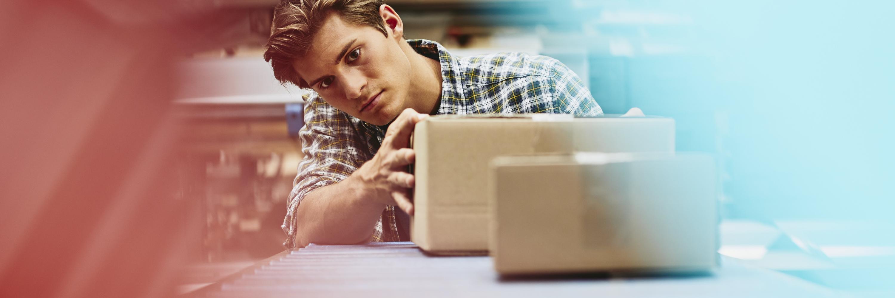 Male blue-collar worker checking parcels. Caucasian man. Checkered shirt. Smooth-shaven chin. Conveyor belt. Logistics environment. Primary color light-red. Secondary colors light- blue and cream.