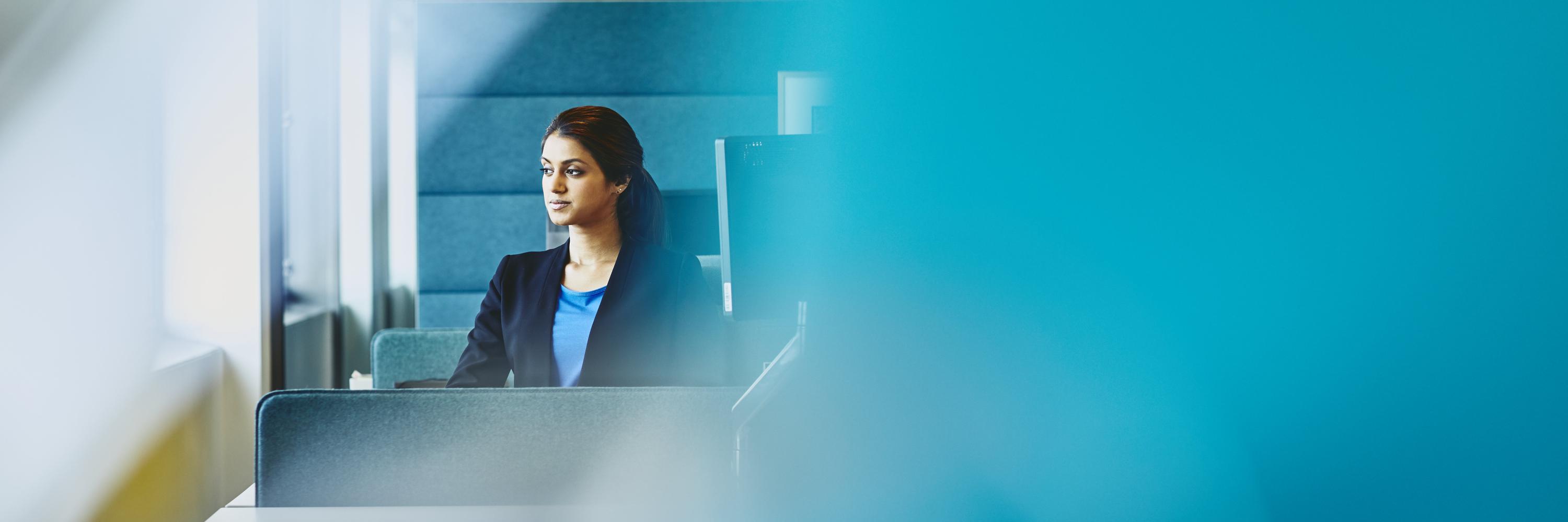 Woman sitting at her desk. India. Primary color: blue.