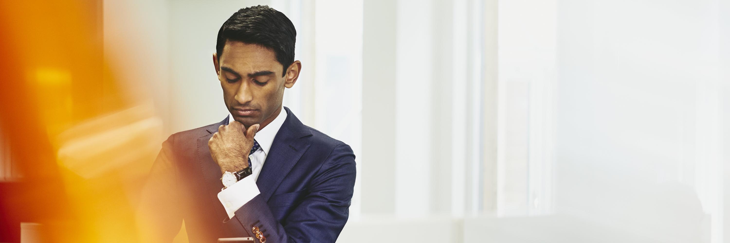 Man in suit looking at his phone. India. Primary color: yellow.