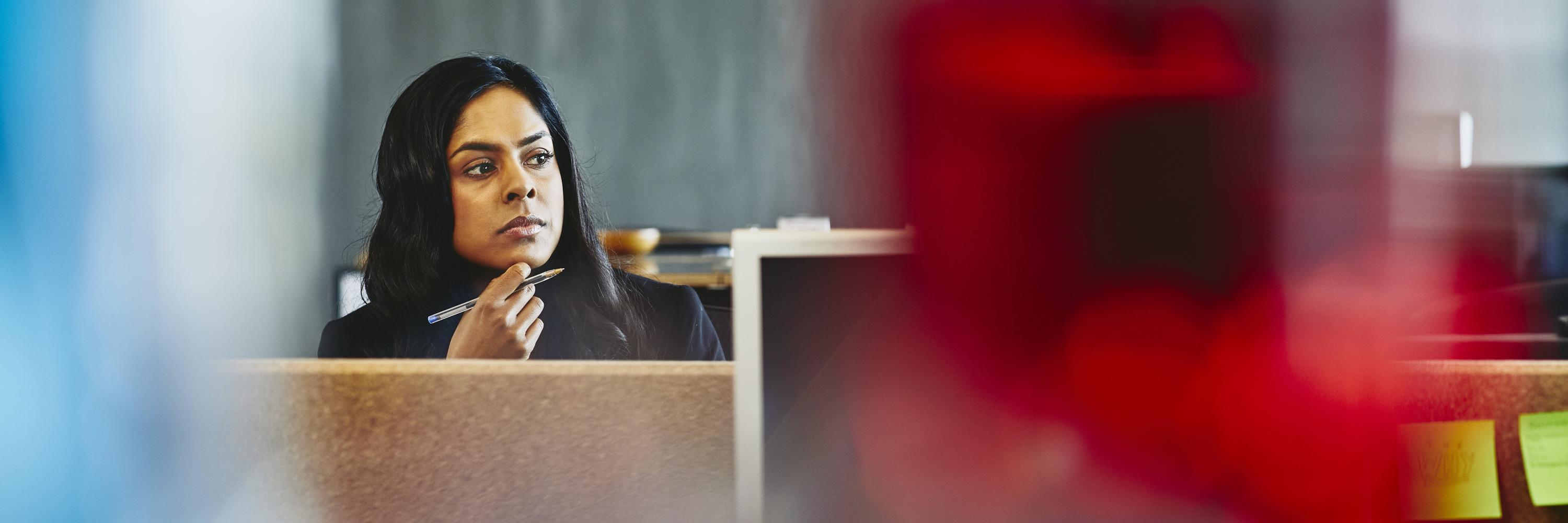 Woman watching over her desk. India. Primary color: red.