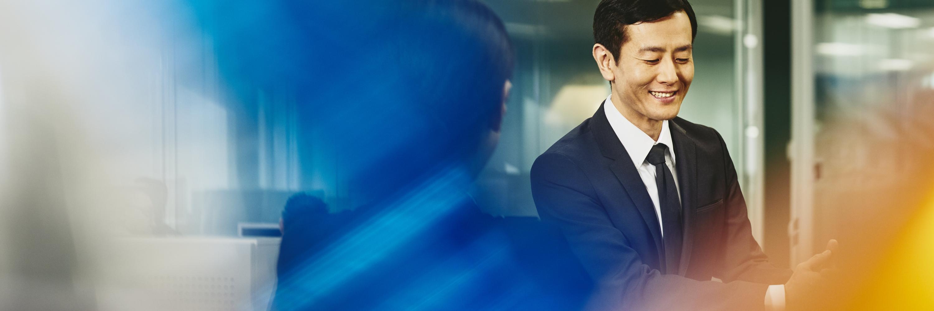 Man and woman talking in an office. Japan. Primary color: blue.