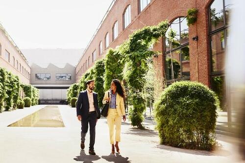 Man and woman walking outside between office buildings.