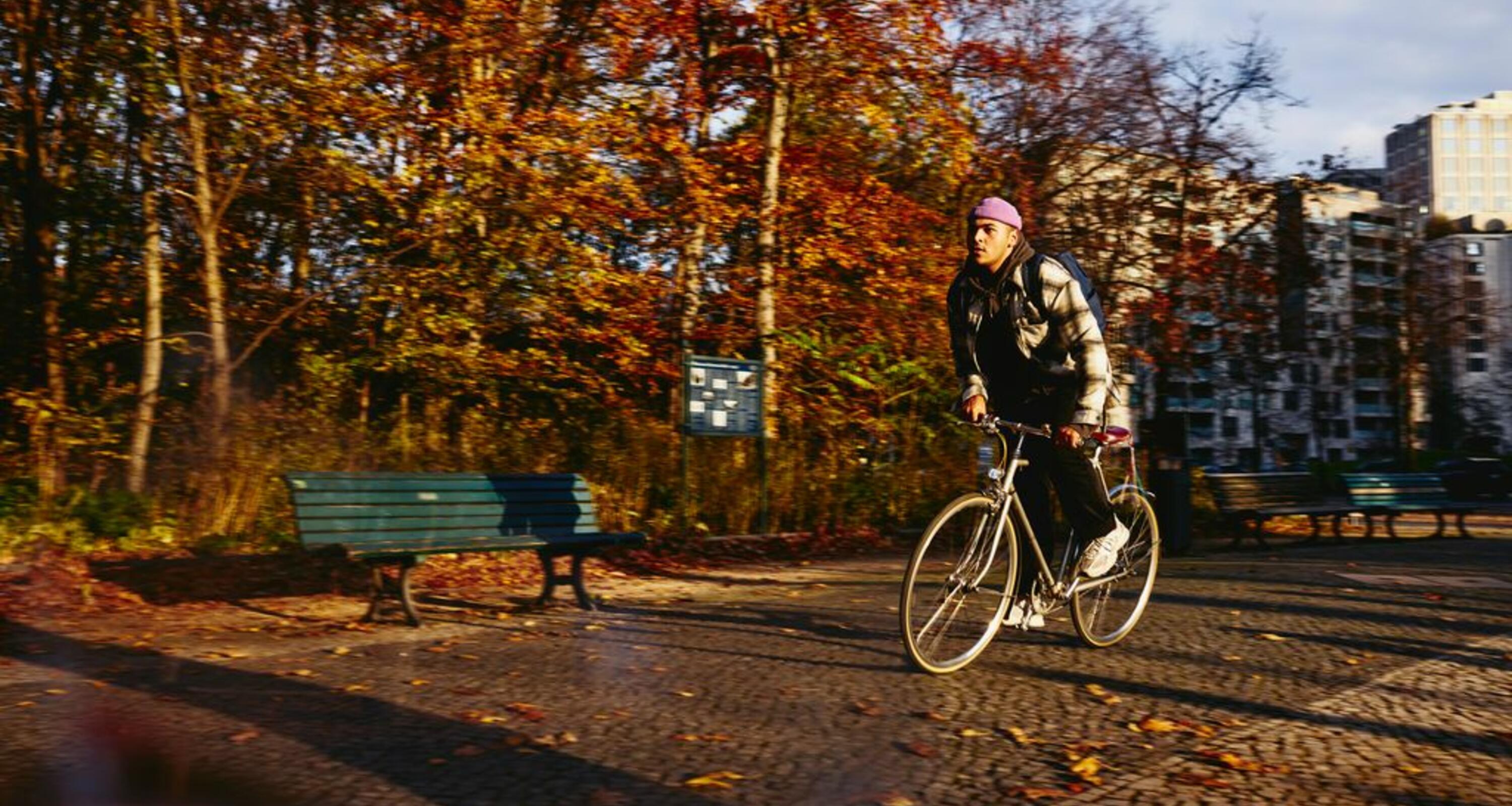 Cycling man, autumn trees and office buildings on the background.