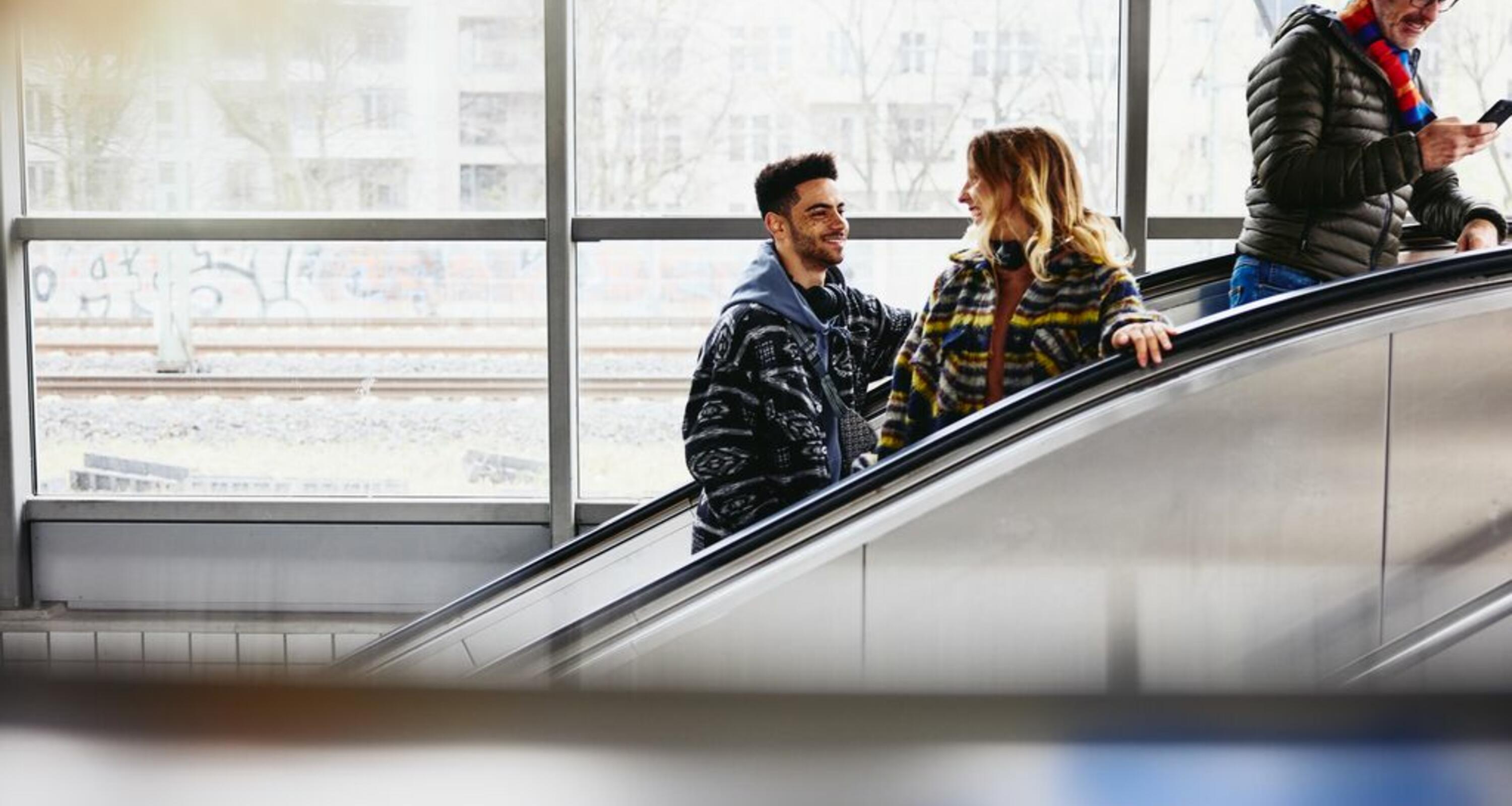 Smiling people on a escalator in a train station.