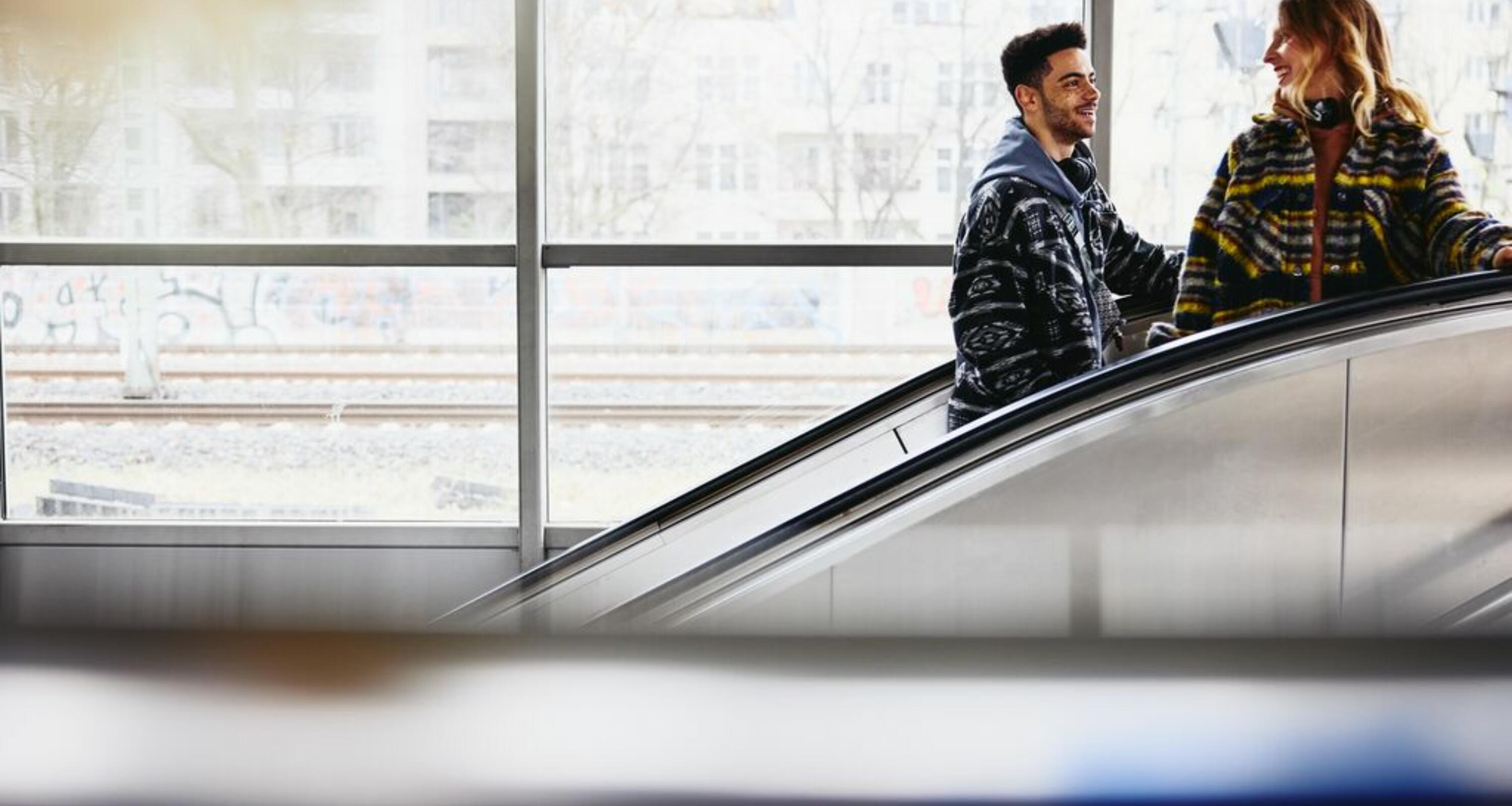 Smiling people on a escalator in a train station.