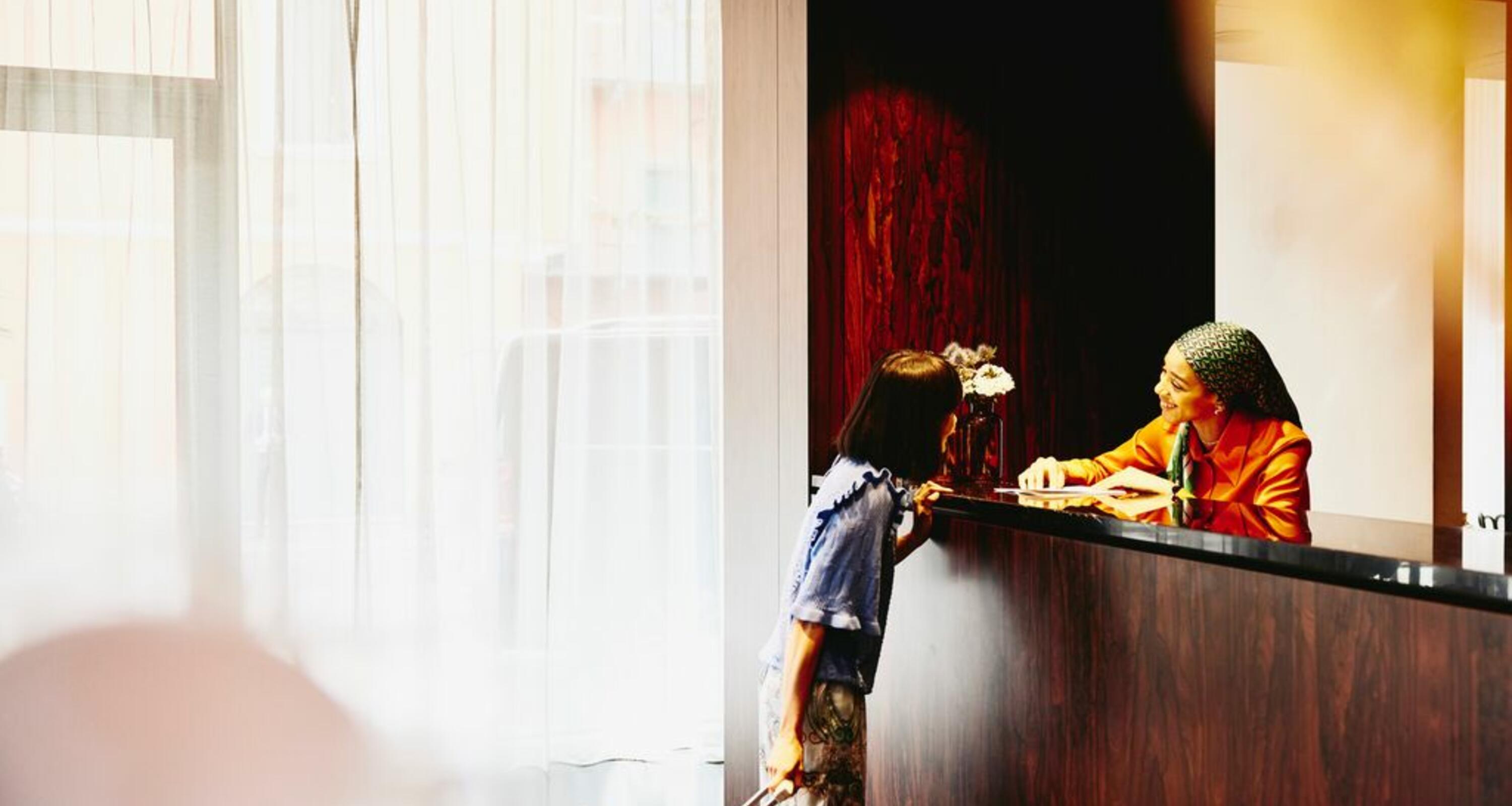 Smiling woman receptionist helping a hotel guest.