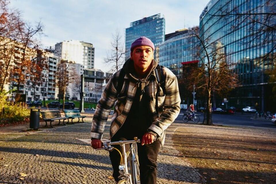 Cycling man, autumn trees and office buildings on the background.