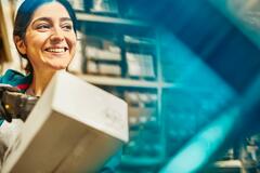 Smiling woman looking away while scanning a package in a warehouse