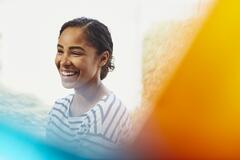 Female worker laughing. African-American woman. Hair up. Striped T-shirt. Primary color yellow. Secondary color blue.
