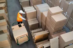 Aerial view of a logistic warehouse worker delivering boxes on a trolley