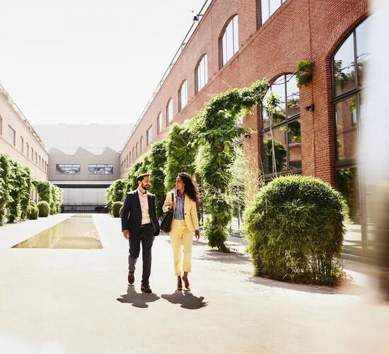 Man and woman walking outside between office buildings.